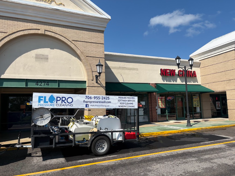 FloPro Pressure Cleaning branded trailer with hose reel and tanks at a commercial job site