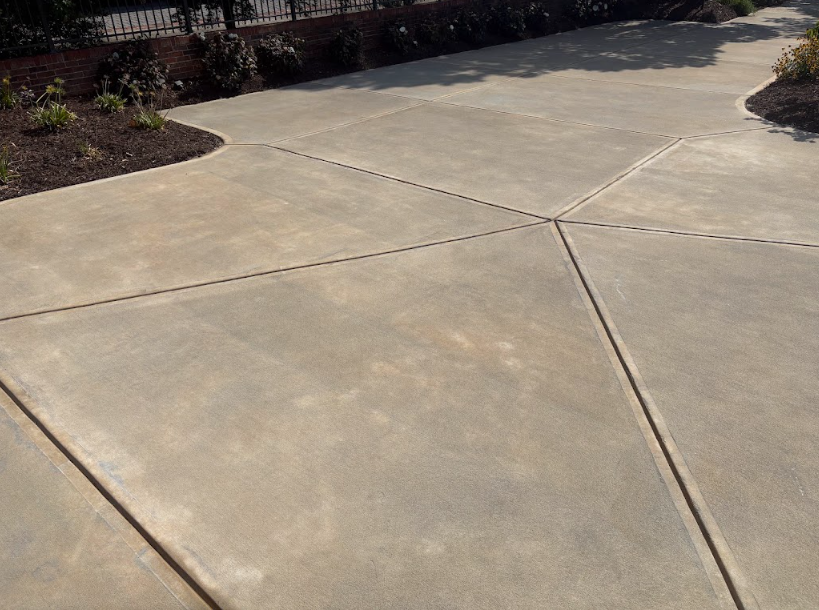 Clean geometric concrete patio and walkway with neat control joints and landscaped beds