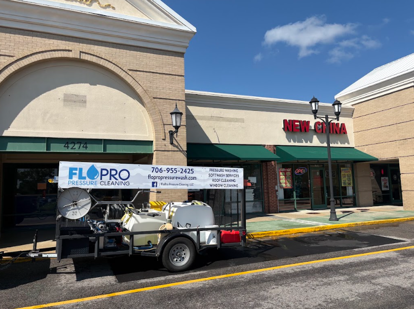 FloPro Pressure Cleaning trailer rig parked outside a shopping center storefront in the CSRA